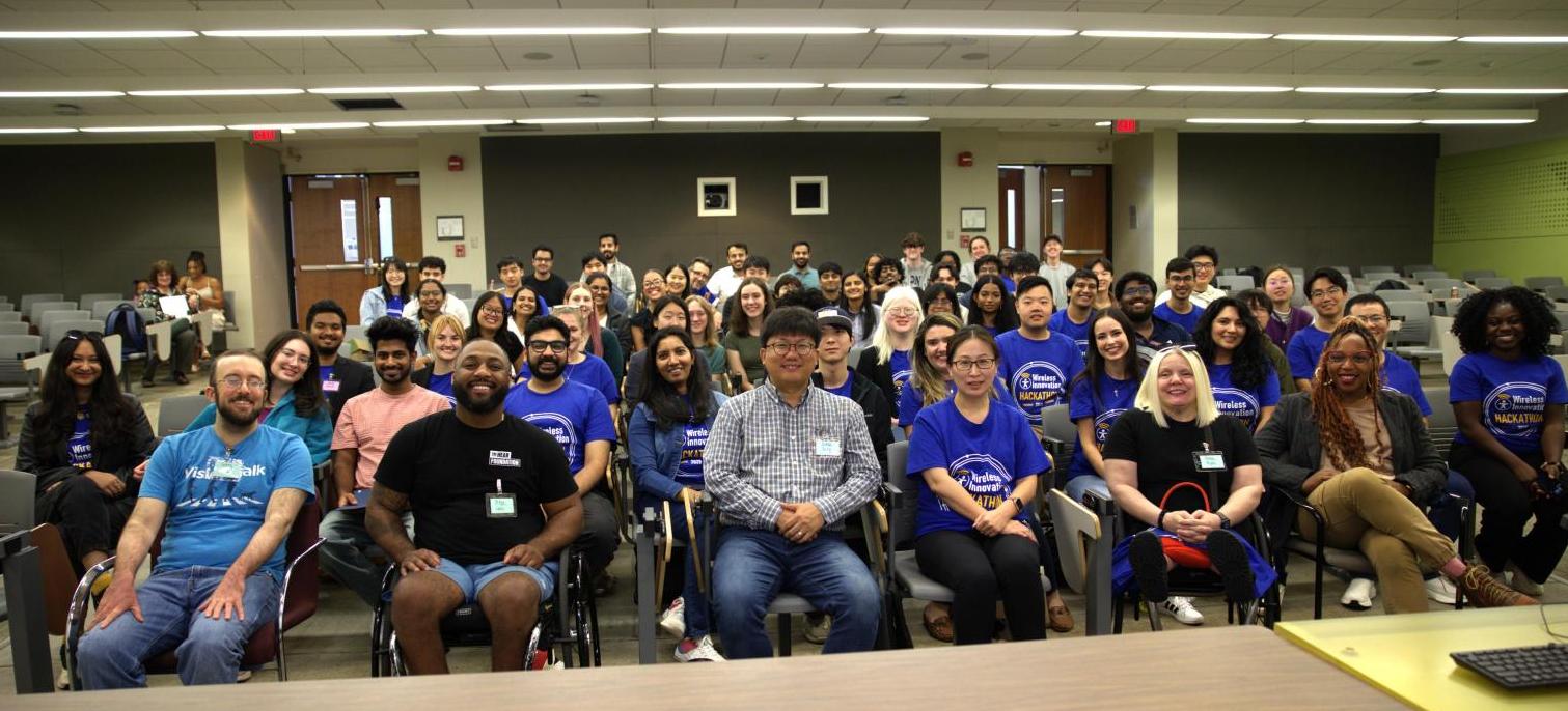 Image of all Hackathon participants seated in an auditorium smiling for a group photo